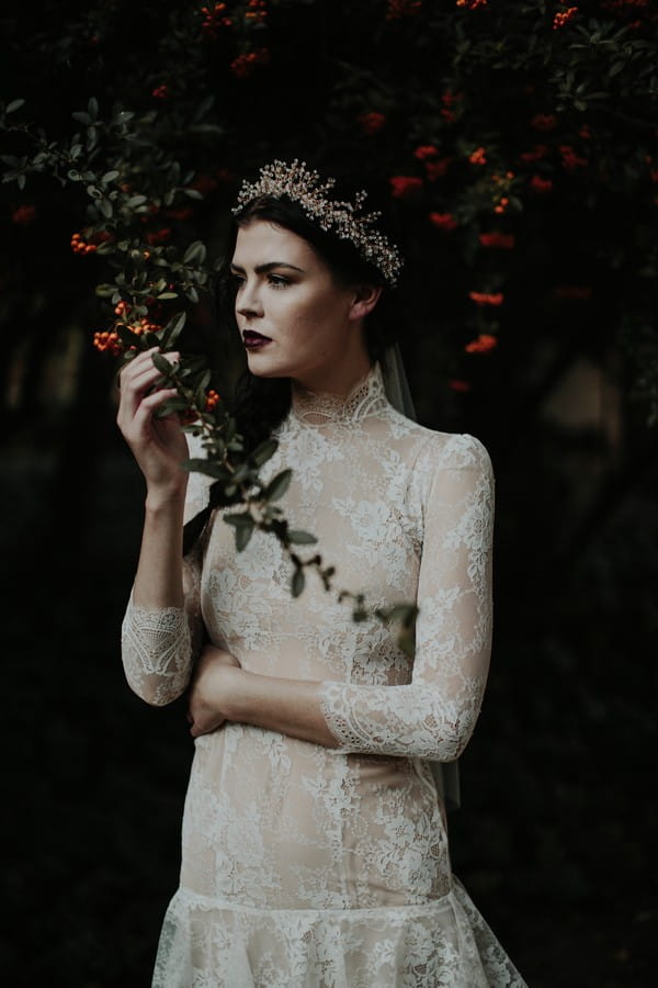 Bride with lace detailed dress standing under tree