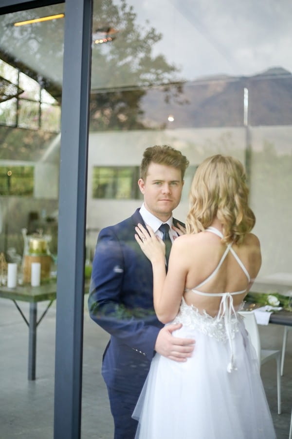 Bride and groom behind window of The Conservatory Franschhoek