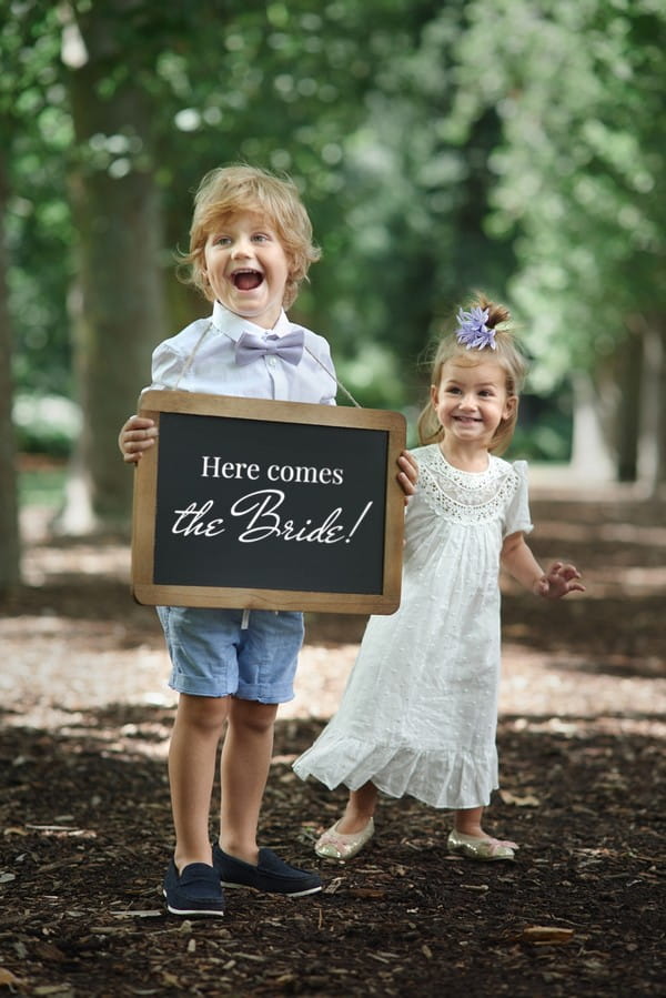 Pageboy holding 'here comes the bride' sign