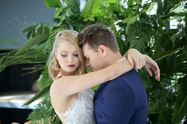 Bride with arms around groom's neck as he rests his head on hers