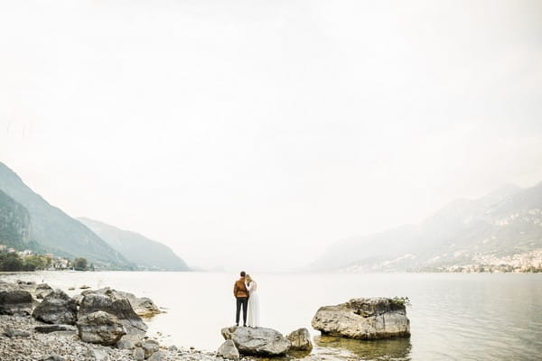 Bride and groom standing on rock at Lake Como