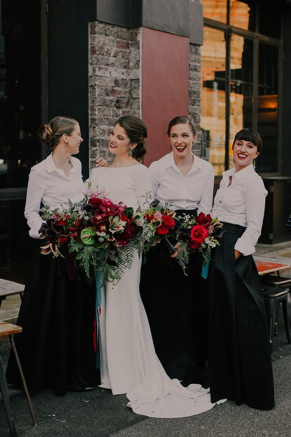 Bride with bridesmaids in white shirts and black skirts