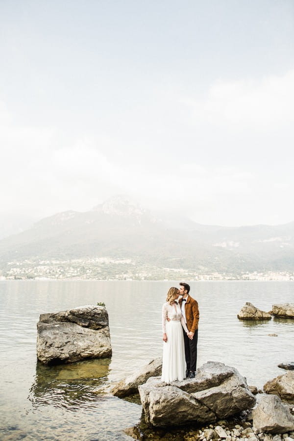 Bride and groom standing on rock at Lake Como