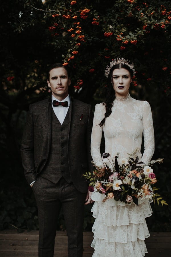 Vintage bride and groom standing next to each other under tree