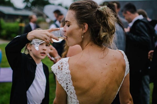 Young girl holding glass to bride's lips as she drinks wine - Picture by Jacqui McSweeney Photography