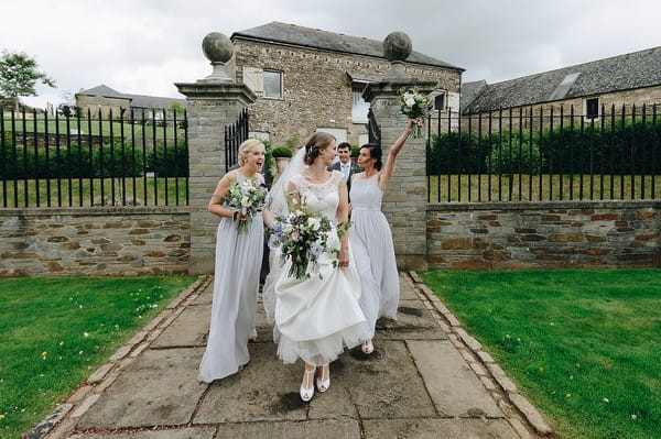 Bridesmaid pulling funny face and raises bouquet in air as she walks with bride - Picture by Michael Marker Photography
