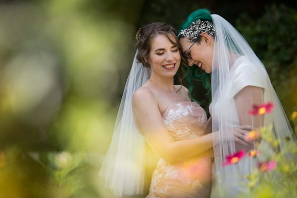 Two bride smiling as they hold each other - Picture by Joel Davies Photography