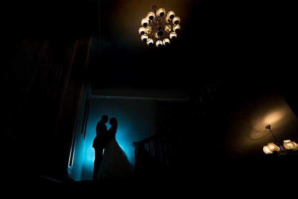 Sihouette of bride and groom in dark room with blue light behind them - Picture by Fiona Forwood Photography