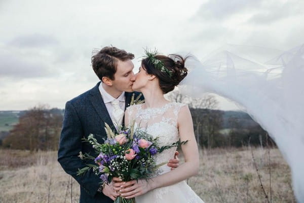 Bride and groom kissing at bride's veil blows in wind - Picture by Rosie Images Photography