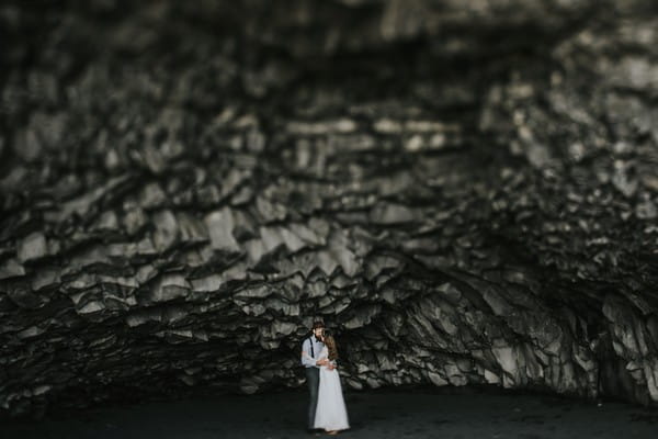 Bride and groom standing under rocks - Picture by Igor Demba Photography