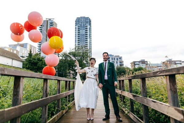 Bride and groom standing on bridge with bride holding balloons - Picture by Jordanna Marston Photography