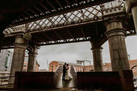 Bride and groom standing on a bridge under a bridge - Picture by Maddie Farris Photography