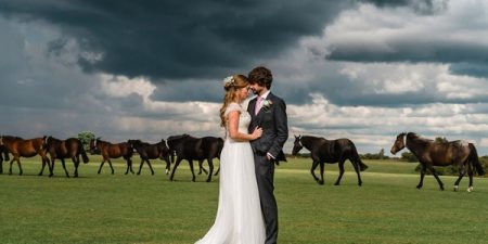 Bride and groom with horses and black clouds in background - Picture by Lemontree Photography