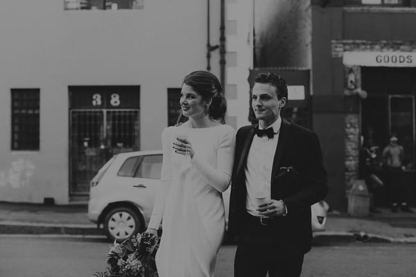 Bride and groom walking holding coffee cups