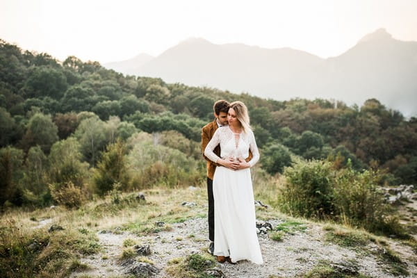 Groom standing behind bride with arms around her waist