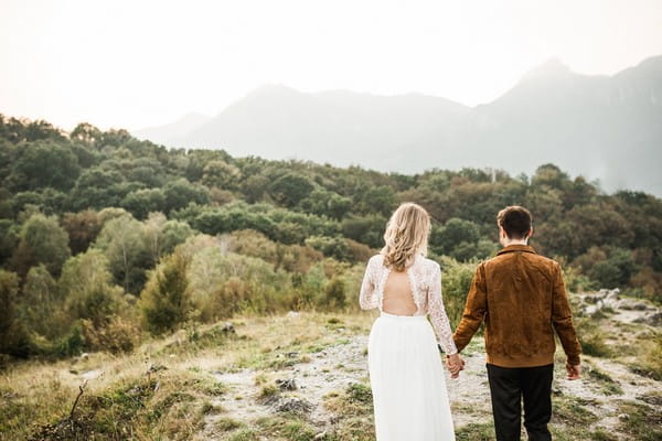 Bride and groom walking across mountain in Lake Como