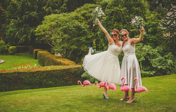 Bride and bridesmaid wearing sunglasses and holding bouquets in the air