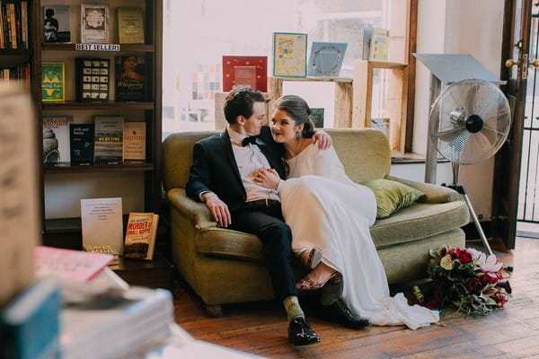 Bride and groom sitting on couch in book shop