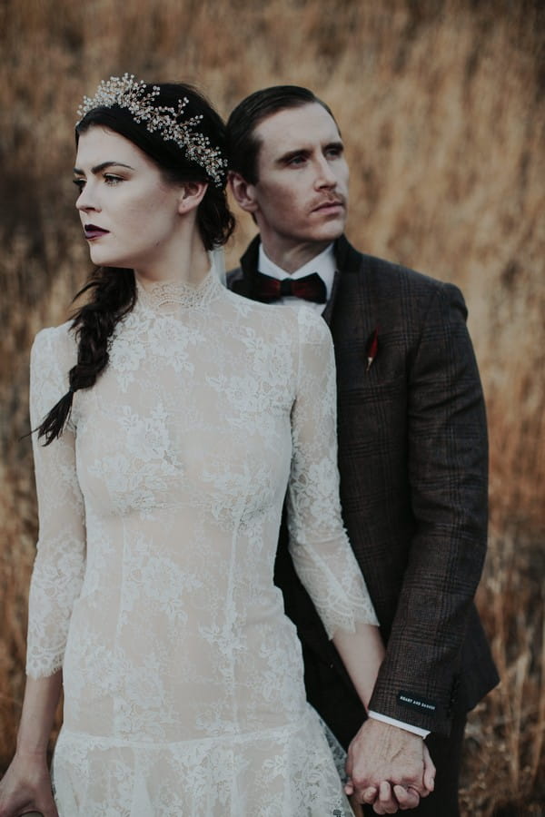 Groom standing behind bride holding her hand