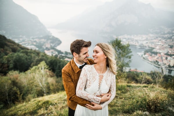 Groom standing behind bride with arms around her waist