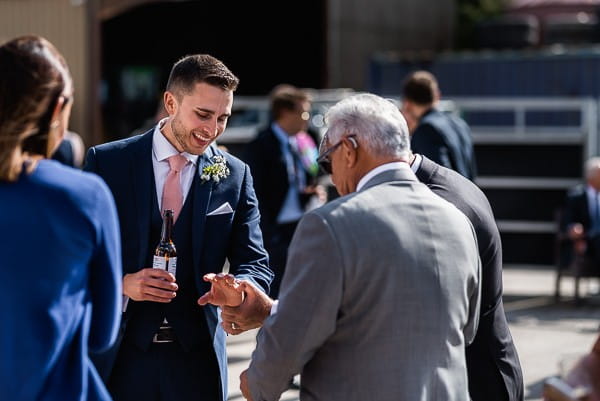 Groom showing guest his wedding ring