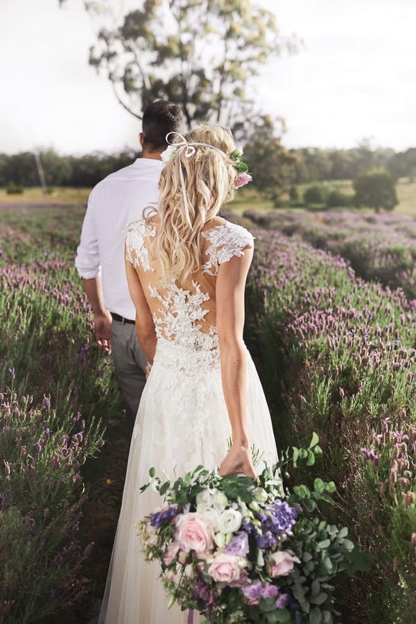 Bride and groom walking through field of lavender