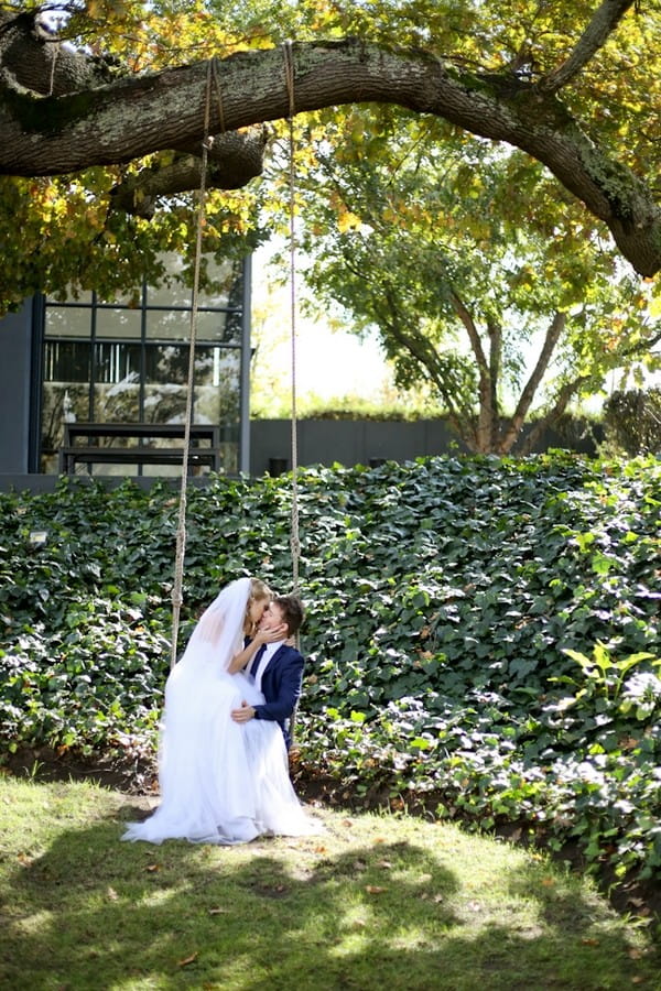 Bride and groom sitting on swing in grounds of The Conservatory Franschhoek