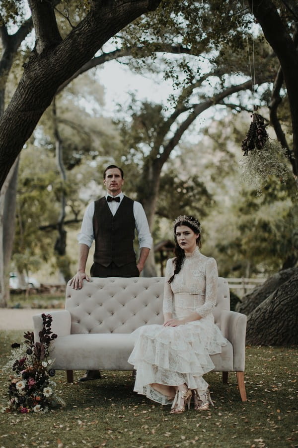 Groom standing behind bride sitting on couch