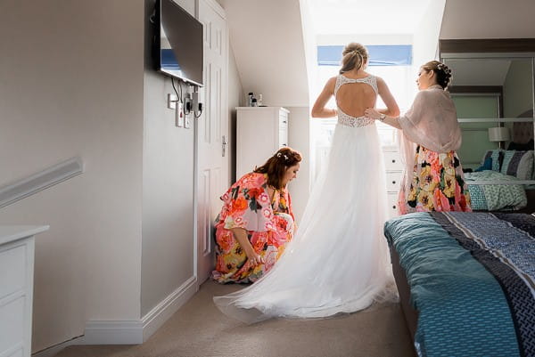 Bridesmaids helping bride with wedding dress