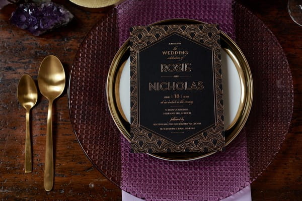 Black wedding stationery on purple plate