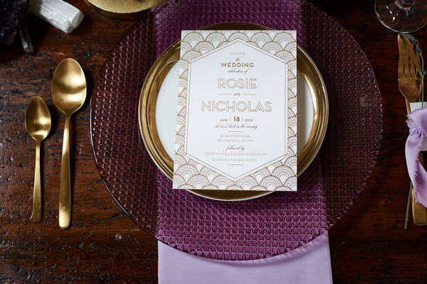 Art-Deco style wedding stationery on purple plate