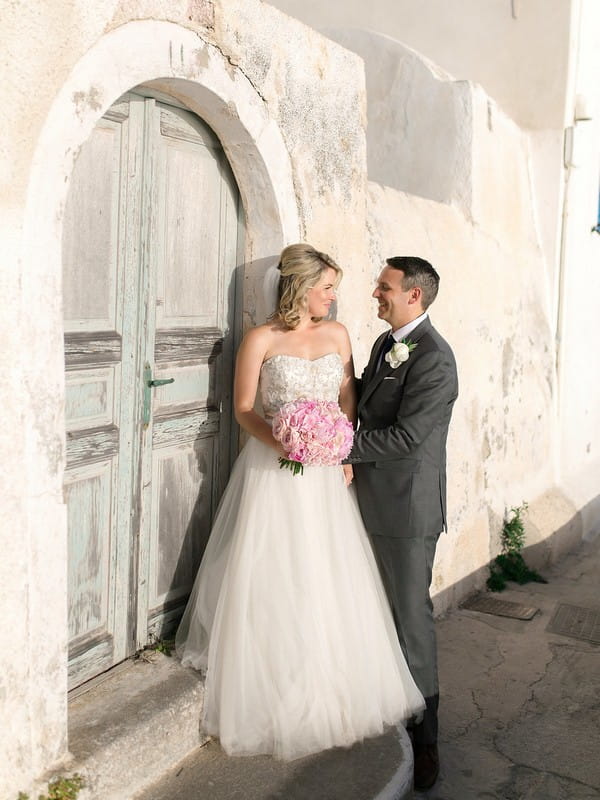 Bride and groom standing in front of old door in Santorini