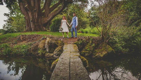 Bride and groom by bridge over lake at Colehayes Park