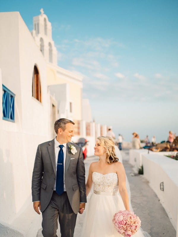 Bride and groom walking down street in Santorini