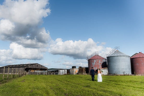 Bride and groom walking across farm