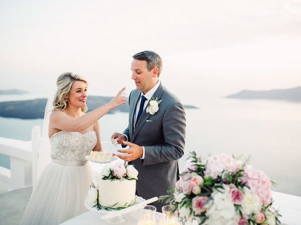 Groom about to eat cake off bride's thumb