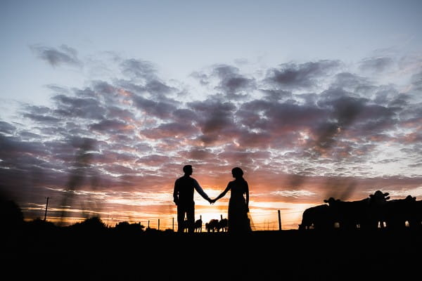 Silhouette of bride and groom against dusky sky