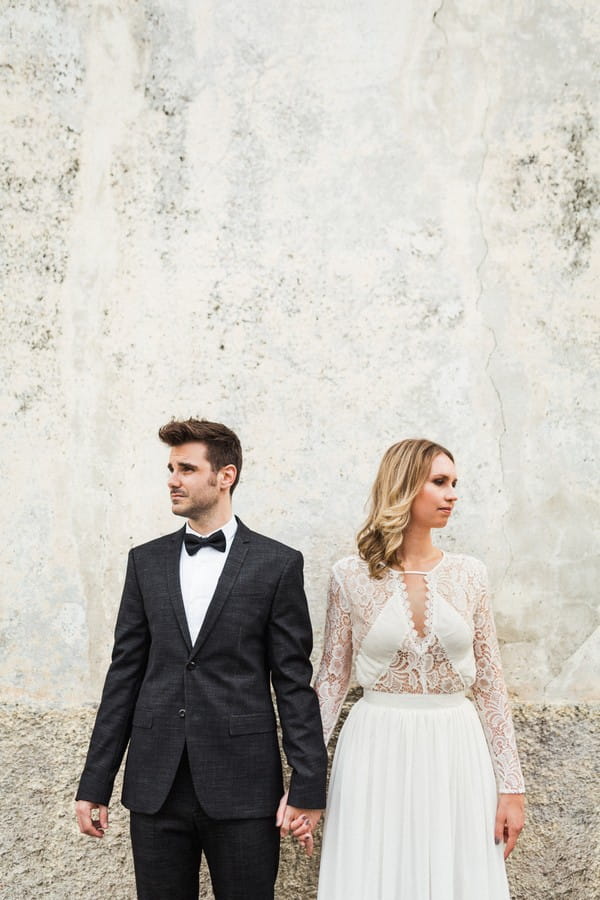 Bride and groom holding hands looking away from each other