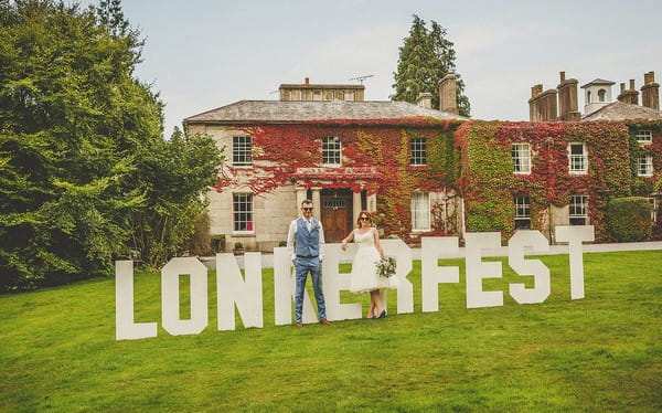 Bride and groom standing in front of Lonkerfest sign at Colehayes Park wedding