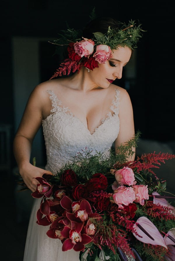 Bride with flower crown holding large maroon bouquet