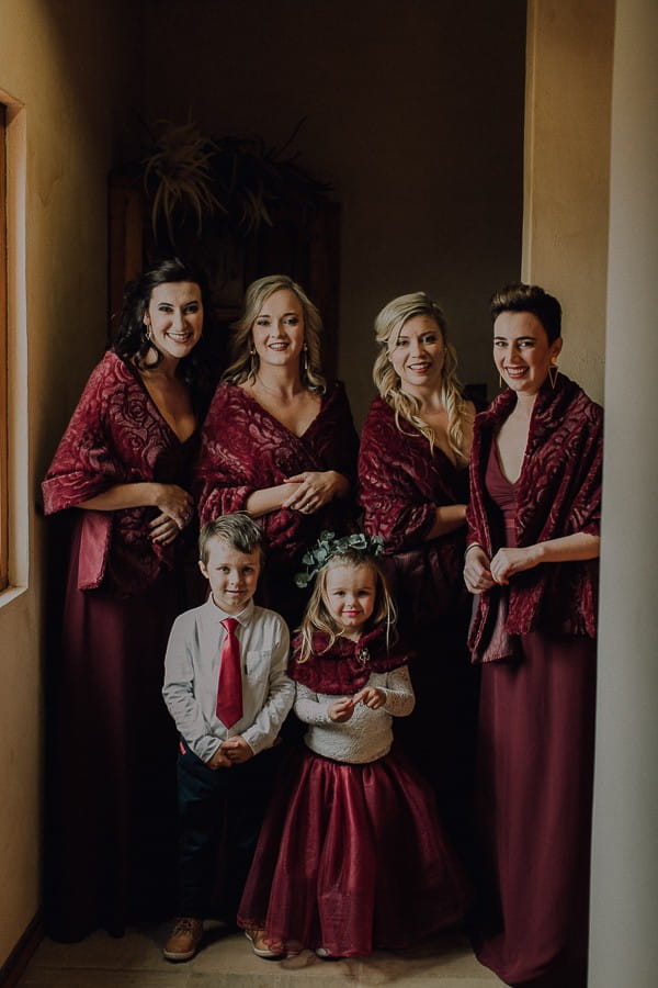 Bridesmaids in burgundy dresses with flower girl and pageboy