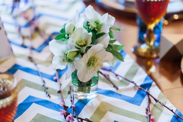 Green and white wedding table flowers on chevron runner