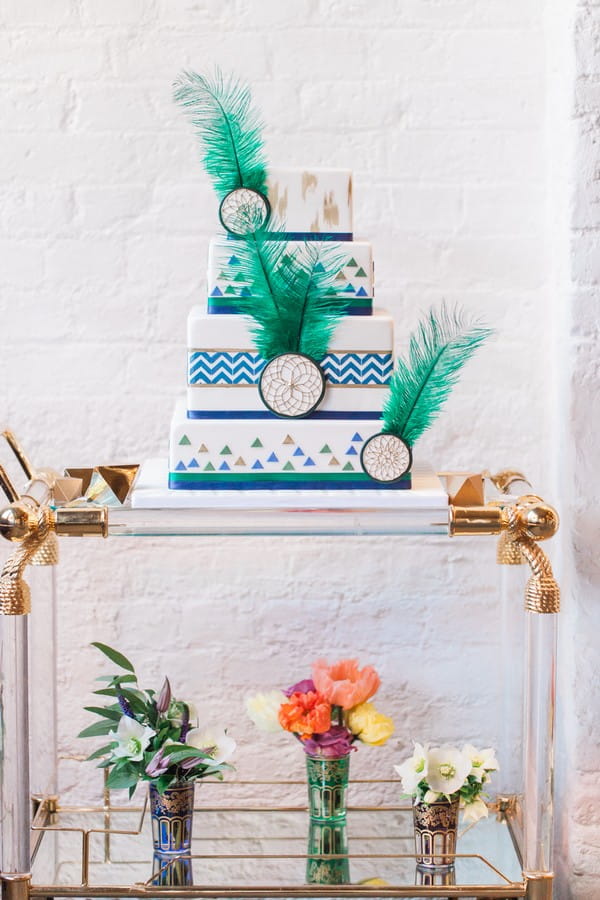 Wedding cake with geometric, green feather and dreamcatcher details on trolley