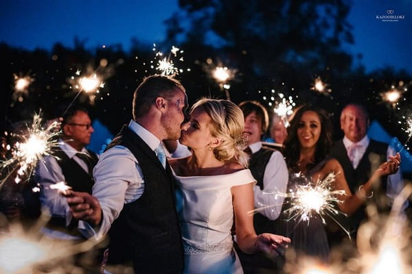 Bride and groom kissing as they and their guests hold sparklers - Picture by Kazooieloki