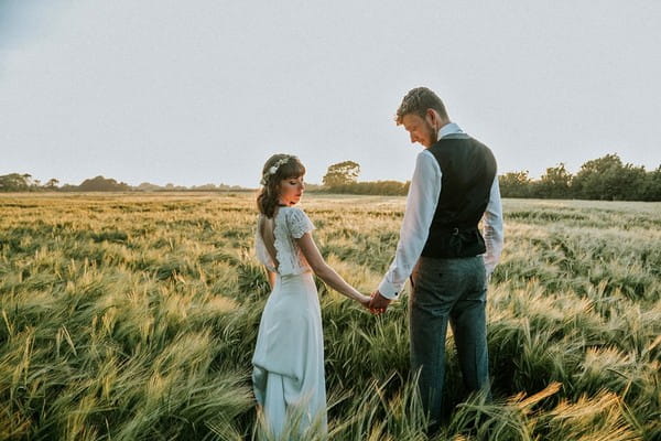 Bride and groom holding hands in long grass - Picture by Ruby-Roux Photography