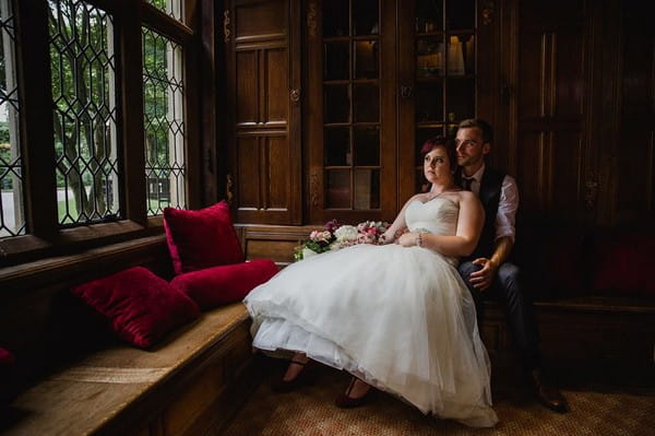 Bride and groom sitting looking out of window of venue - Picture by Helen King Photography