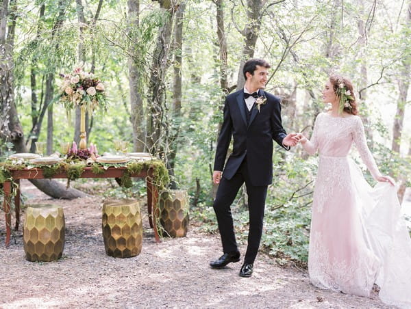 Bride and groom by wedding table in woods