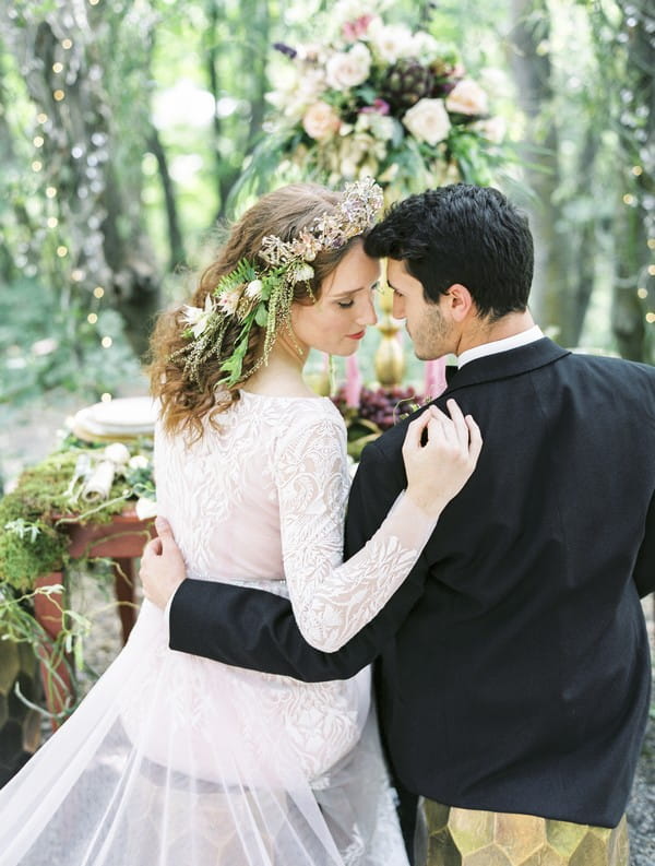 Bride and groom sitting at wedding table touching heads