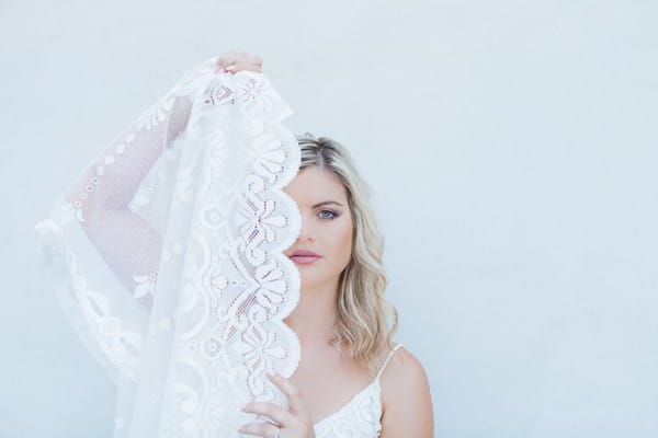 Bride holding lace across face