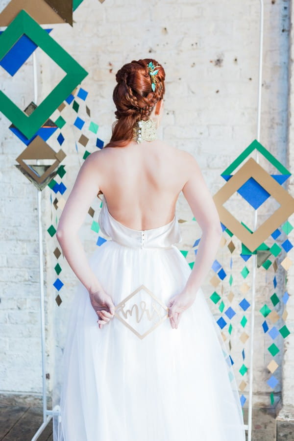 Bride holding geometric Mrs sign behind her back